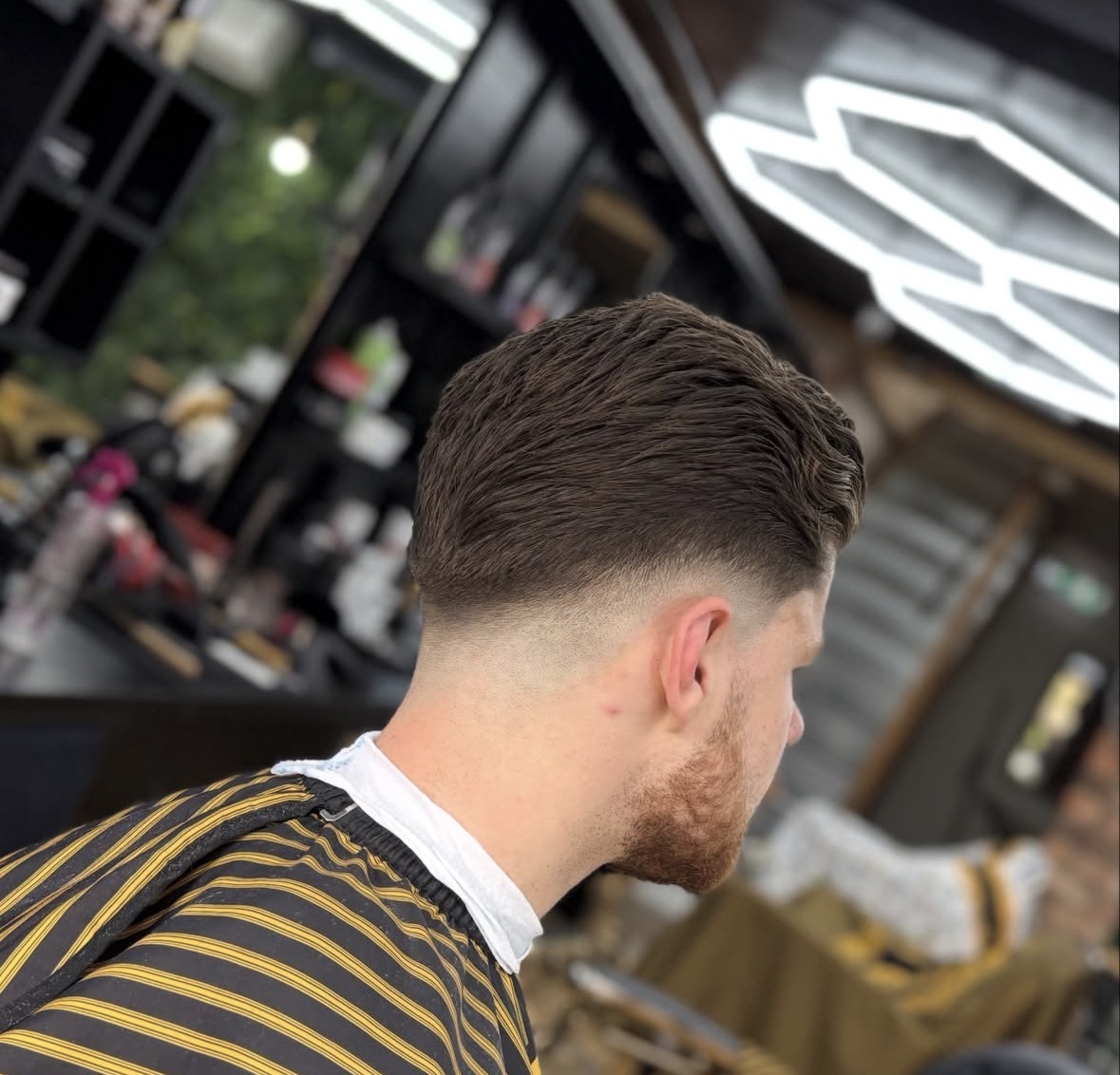 Mid fade with textured pompadour styling, from the back and side